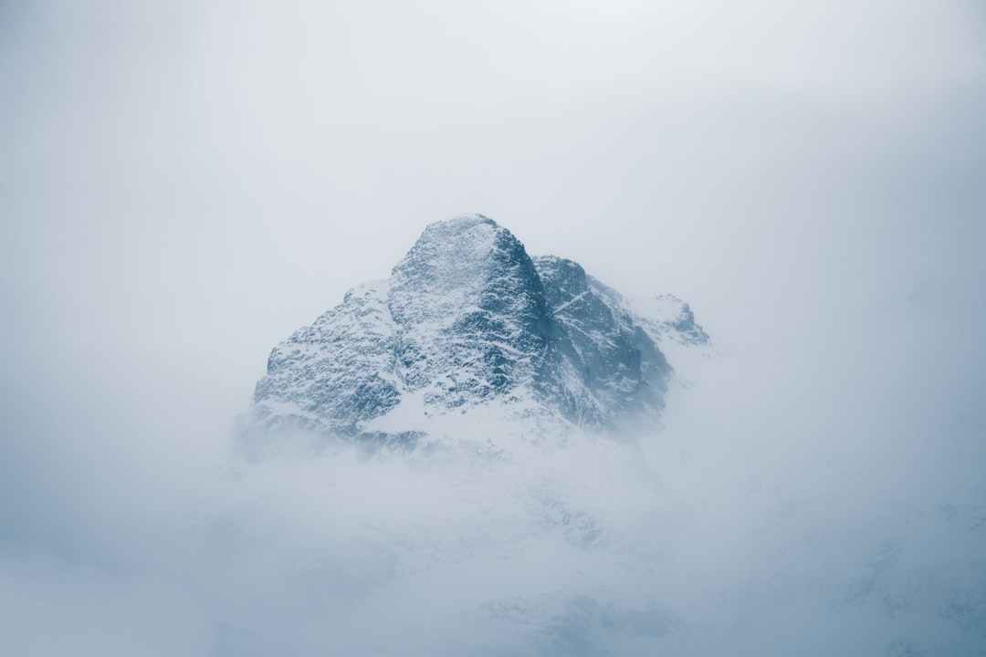 Snow-covered mountain peak emerging from clouds